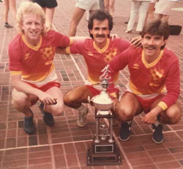 Adrian Brooks, Bobby McAvan, and Max Thompson posing with a soccer trophy